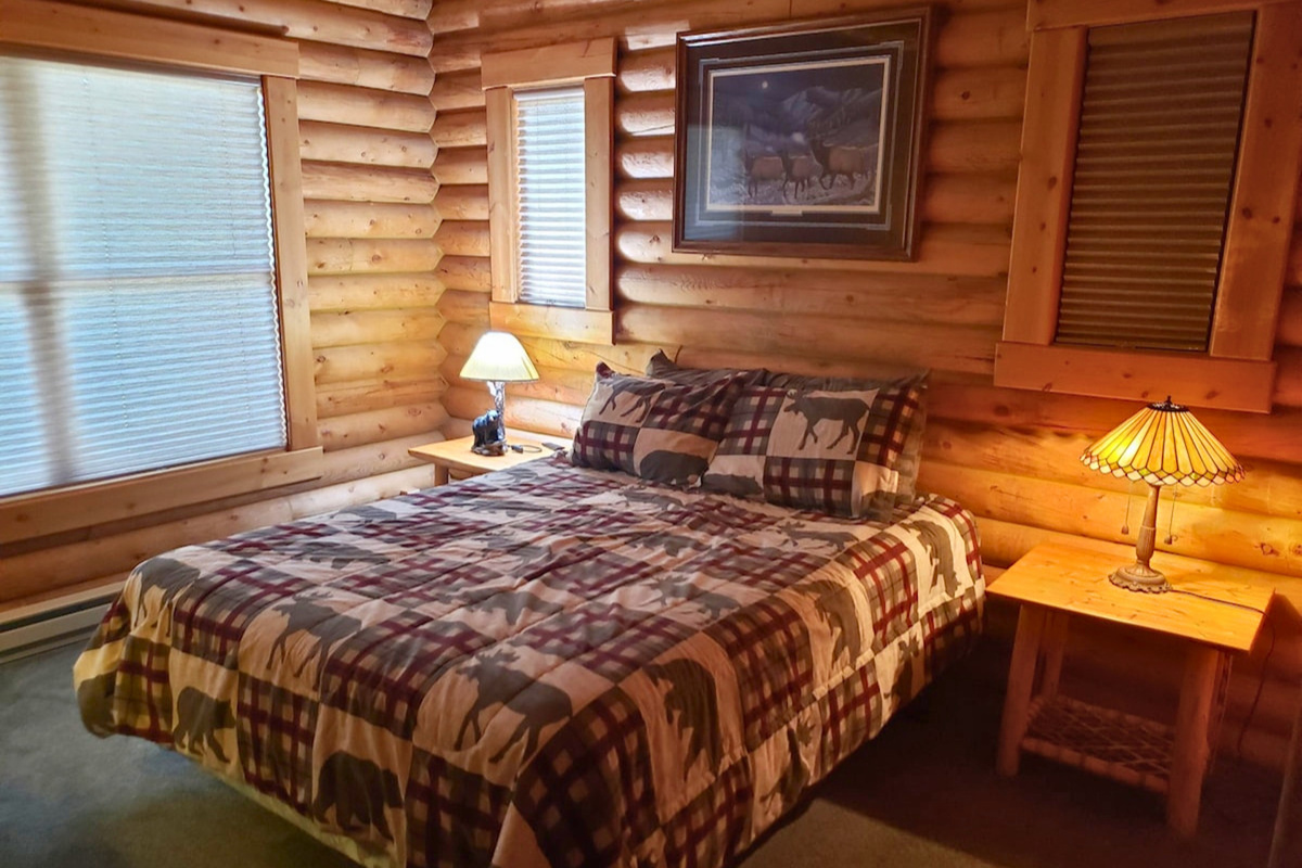 Bedroom 1: queen bed, enjoy tasteful cabin decor, warm lighting, and a large window.