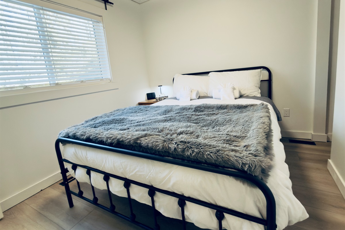 Queen bedroom from another angle showing bedside table and window
