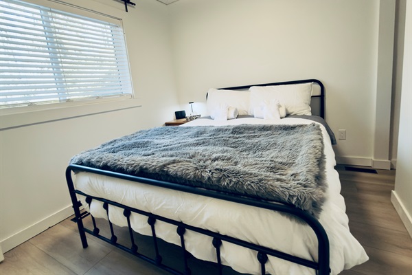 Queen bedroom from another angle showing bedside table and window