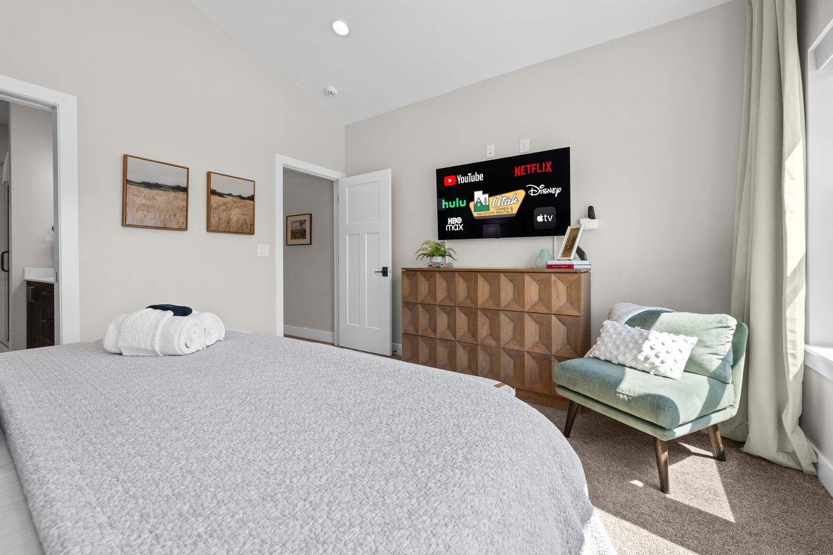 Relax in the peaceful primary retreat with a king bed, cozy seating area, and expansive windows overlooking the Ogden Valley mountains.