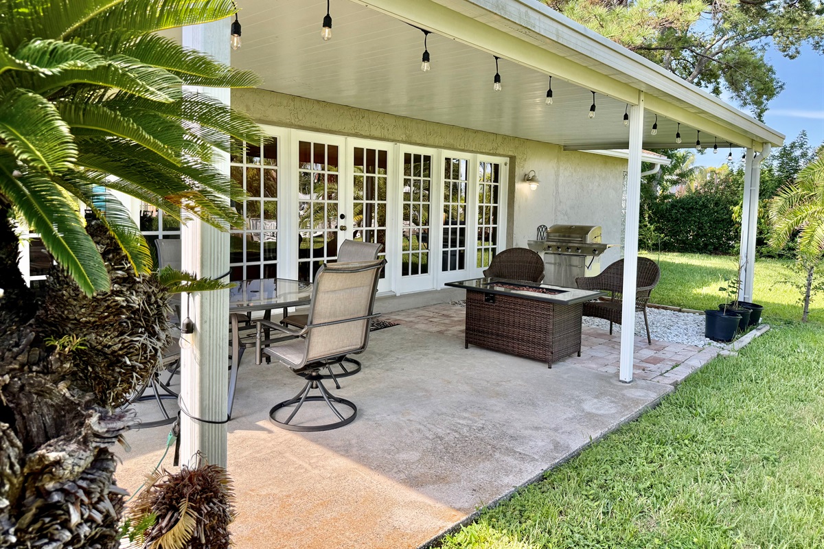 Enjoy sunny days and breezy evenings on this covered patio featuring a glass dining table, comfy swivel chairs, and a cozy lounge area for ultimate relaxation.