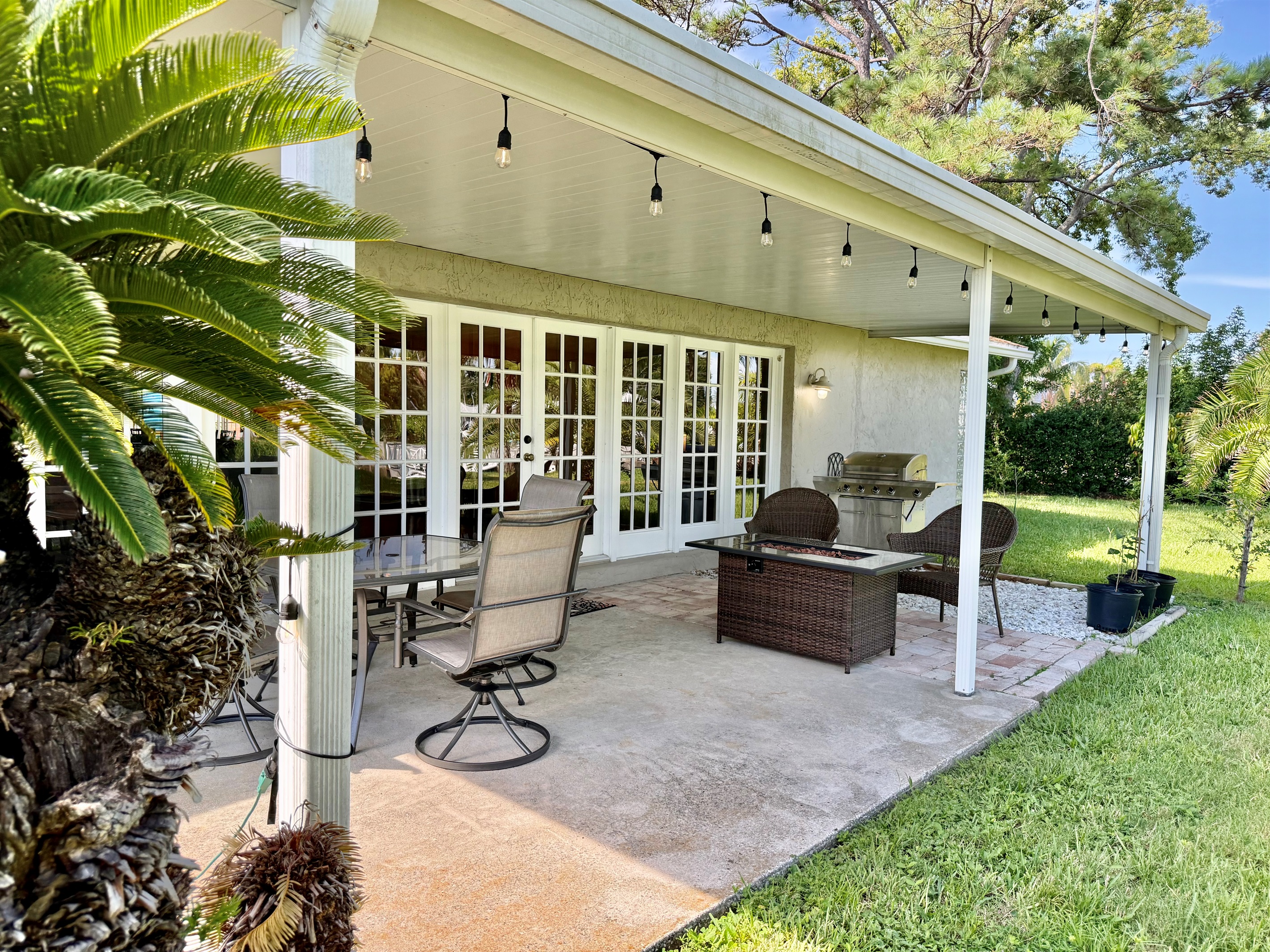 Enjoy sunny days and breezy evenings on this covered patio featuring a glass dining table, comfy swivel chairs, and a cozy lounge area for ultimate relaxation.