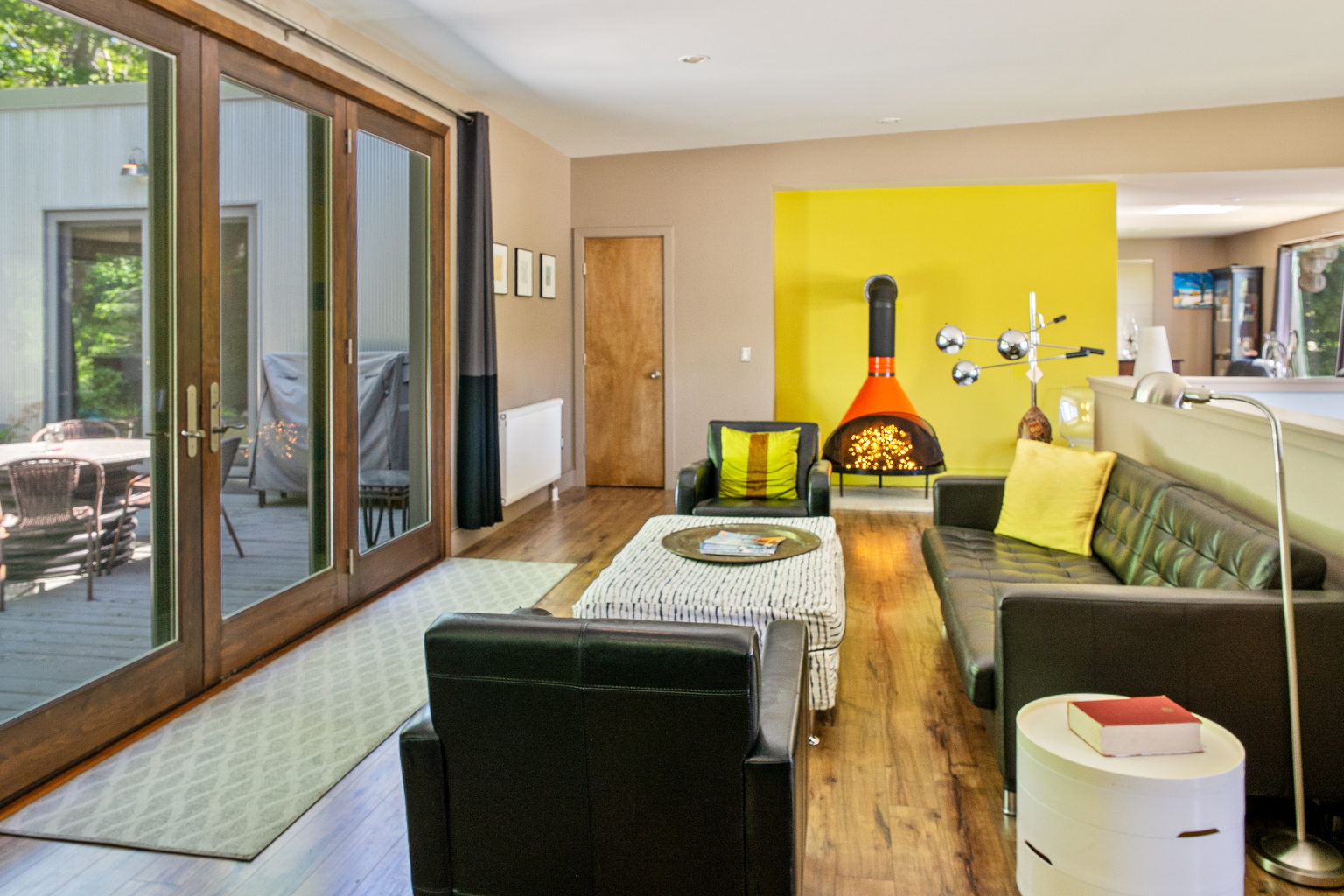 Modern mid-century lounge on the main level featuring a decorative vintage stove and designer seating. This bright social hub opens directly to the 33ft deck, offering a seamless indoor-outdoor connection to the Acadia National Park border.