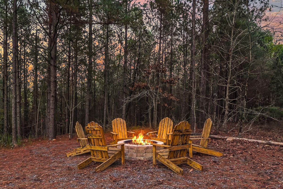 Fire pit area with Adirondack chairs nestled among the trees.