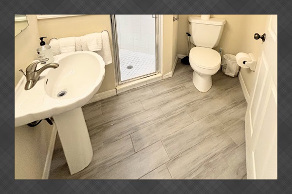 Bathroom with pedestal sink, walk-in shower, toilet, and clean neutral finishes.