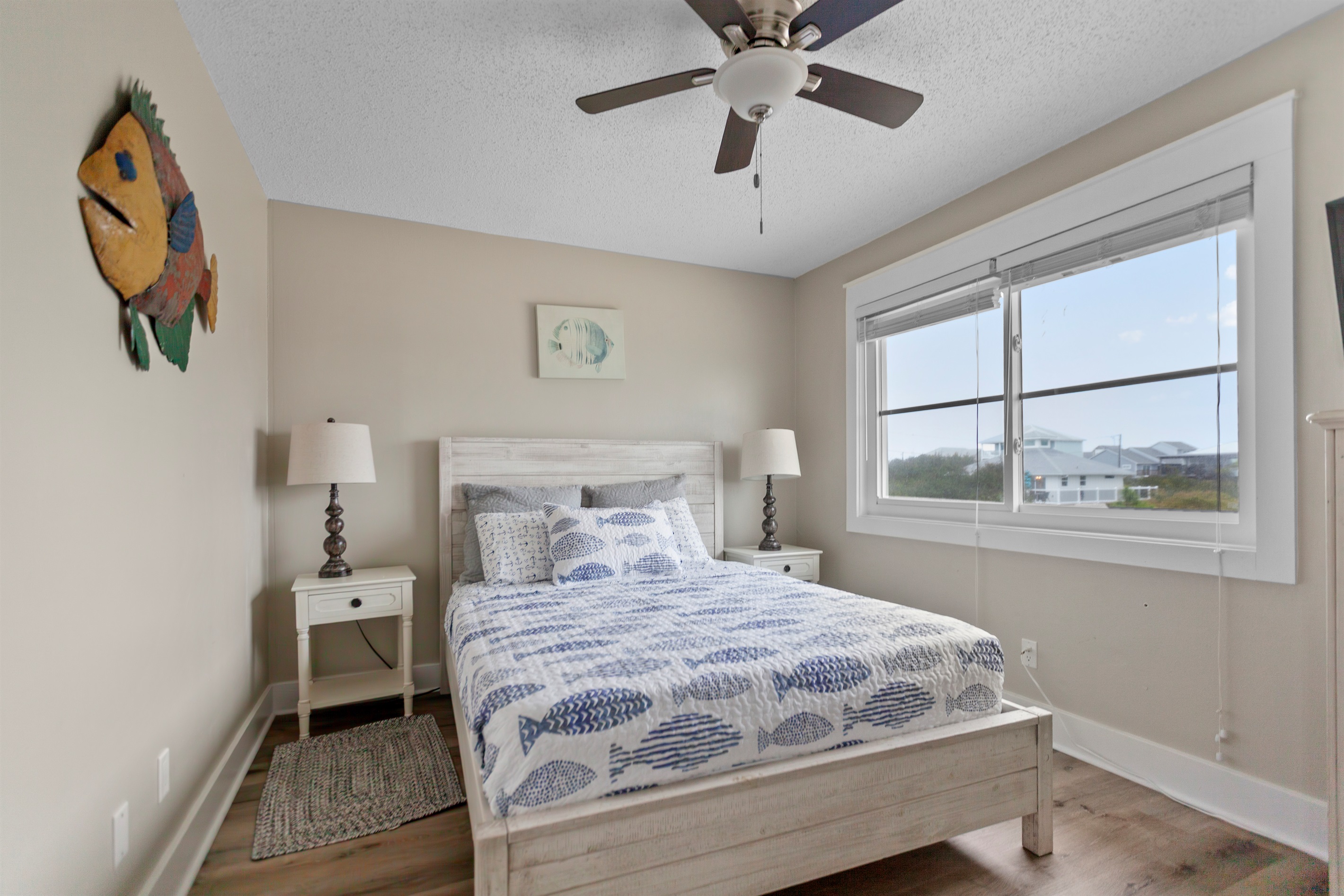 Cozy second bedroom with soft coastal tones and plenty of natural light - the perfect place for family or friends to relax after a fun day on the beach