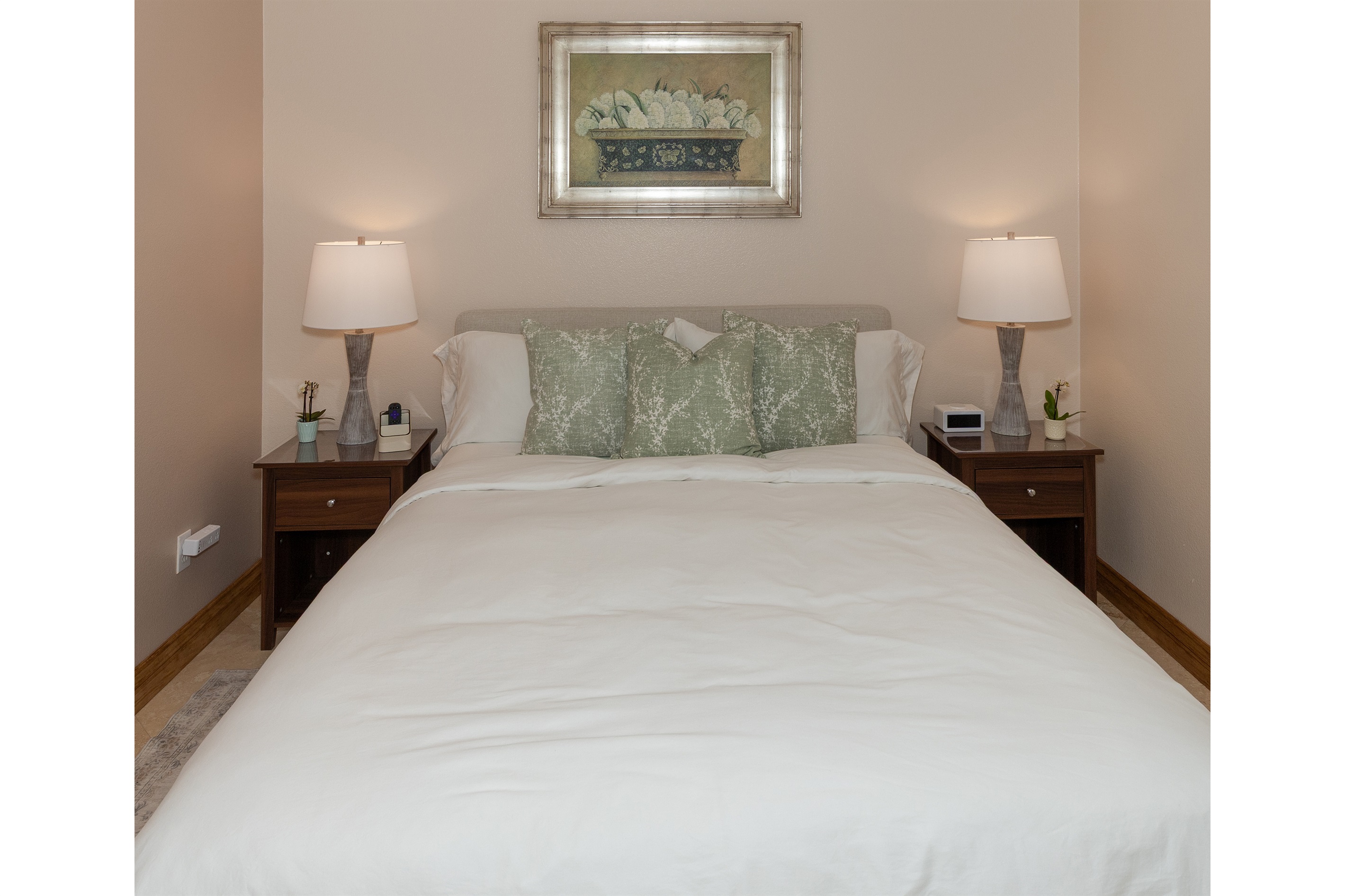 Comfortable queen bed with soft linens and bedside lighting