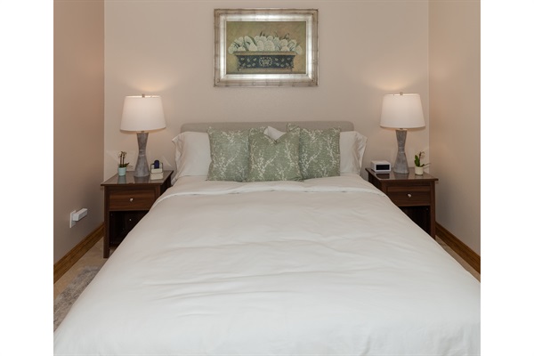 Comfortable queen bed with soft linens and bedside lighting