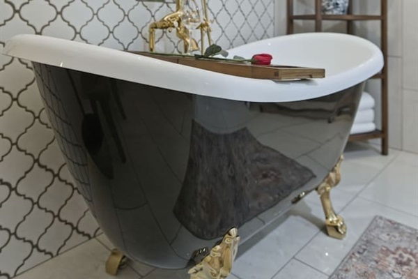 Stylish clawfoot tub with gold detailing, set against elegant patterned tiles for a relaxing and refined soak
