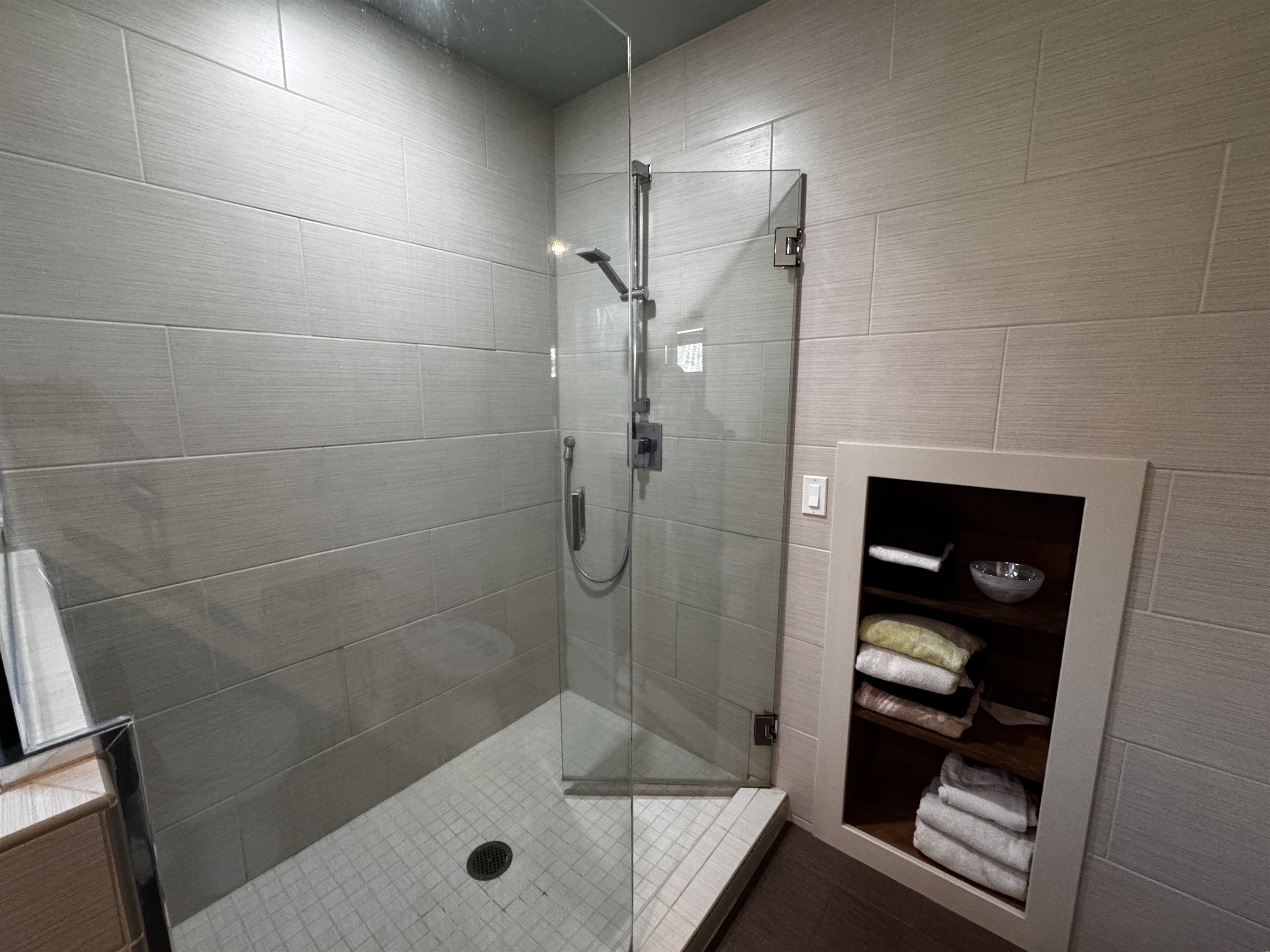 Custom floor-to-ceiling tiled shower in the primary ensuite. This modern glass enclosure features premium fixtures and built-in linen storage, providing a clean, spa-like experience at the heart of the master wing.