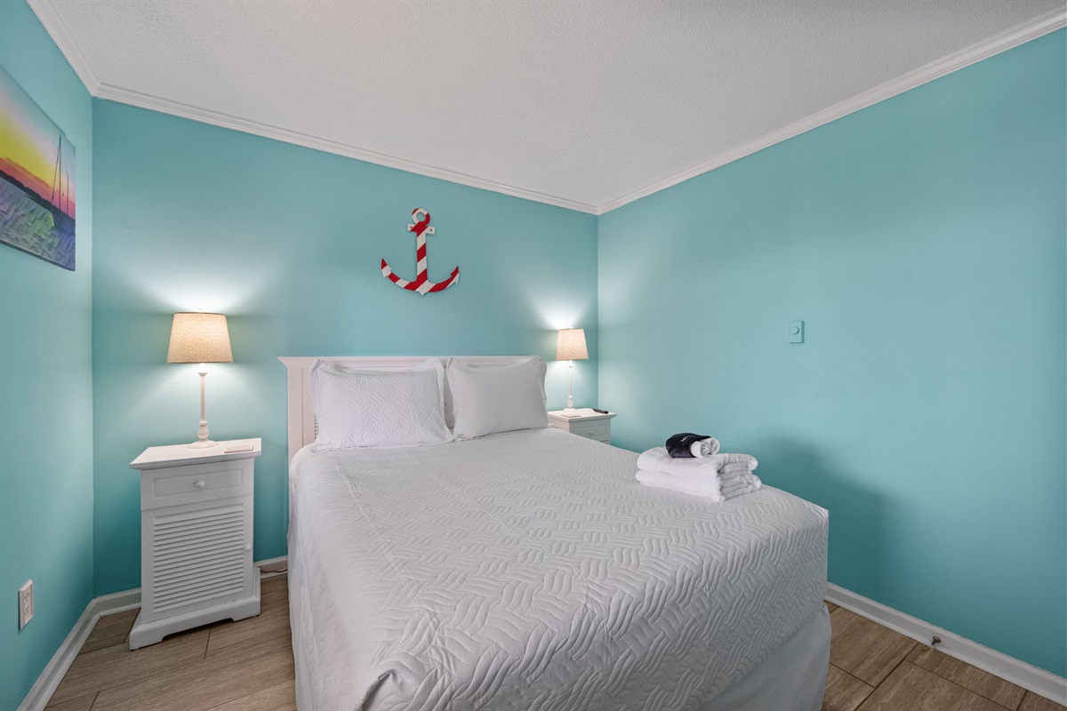 Rest easy in this inviting queen bedroom featuring soft natural light and a calm beach-inspired design