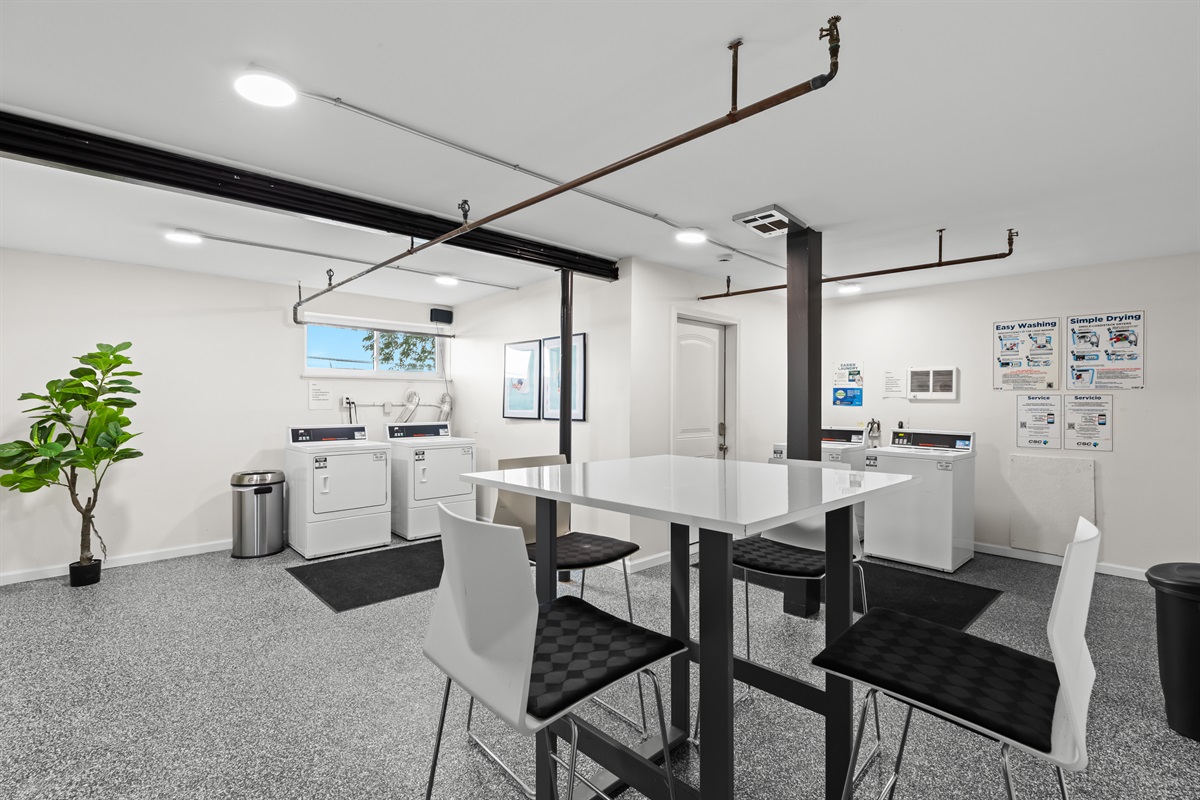 Shared laundry room with folding station and updated appliances for guest convenience.
