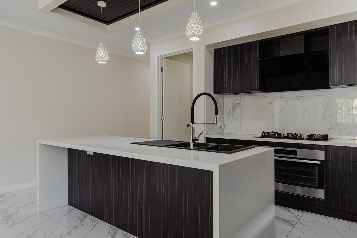 Modern kitchen with island bench, gas cooktop, oven, rangehood and pendant lighting.