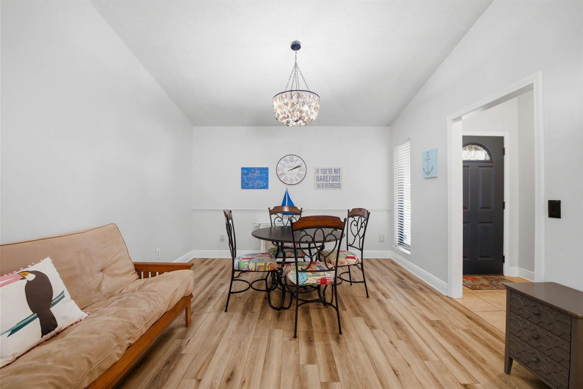 This bright dining area offers a welcoming space for meals and gatherings. Featuring warm wood flooring, a charming chandelier, and comfortable seating, the room creates a relaxed atmosphere perfect for everyday dining or entertaining guests.