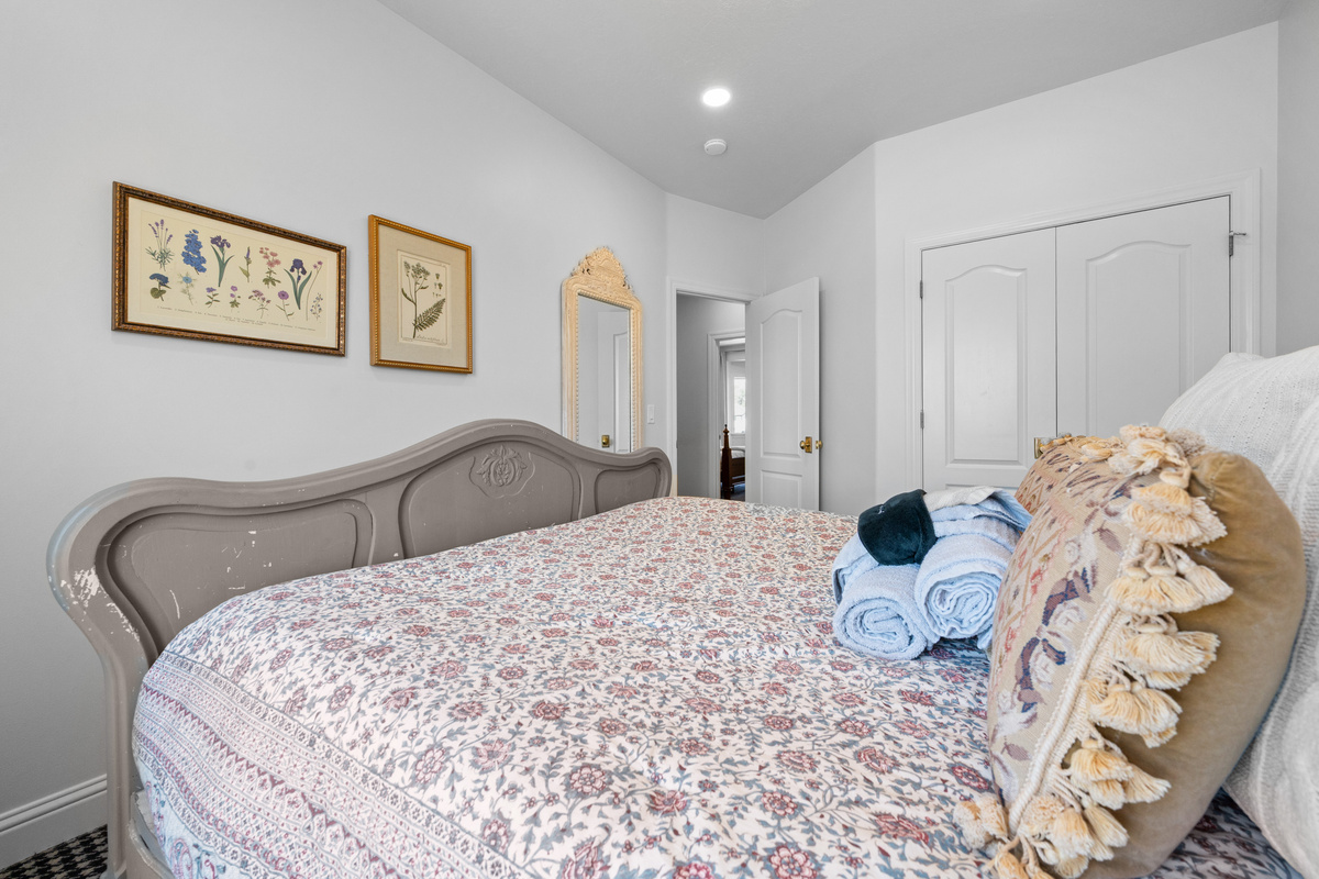 This graceful queen bedroom combines botanical artwork, layered textiles, generous closet storage, and a soft neutral palette for a restful retreat.