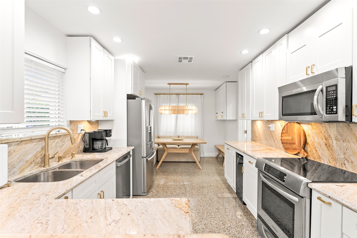 Clean lines, quartz-style stone countertops, and gold accents create a refined yet relaxed cooking space.