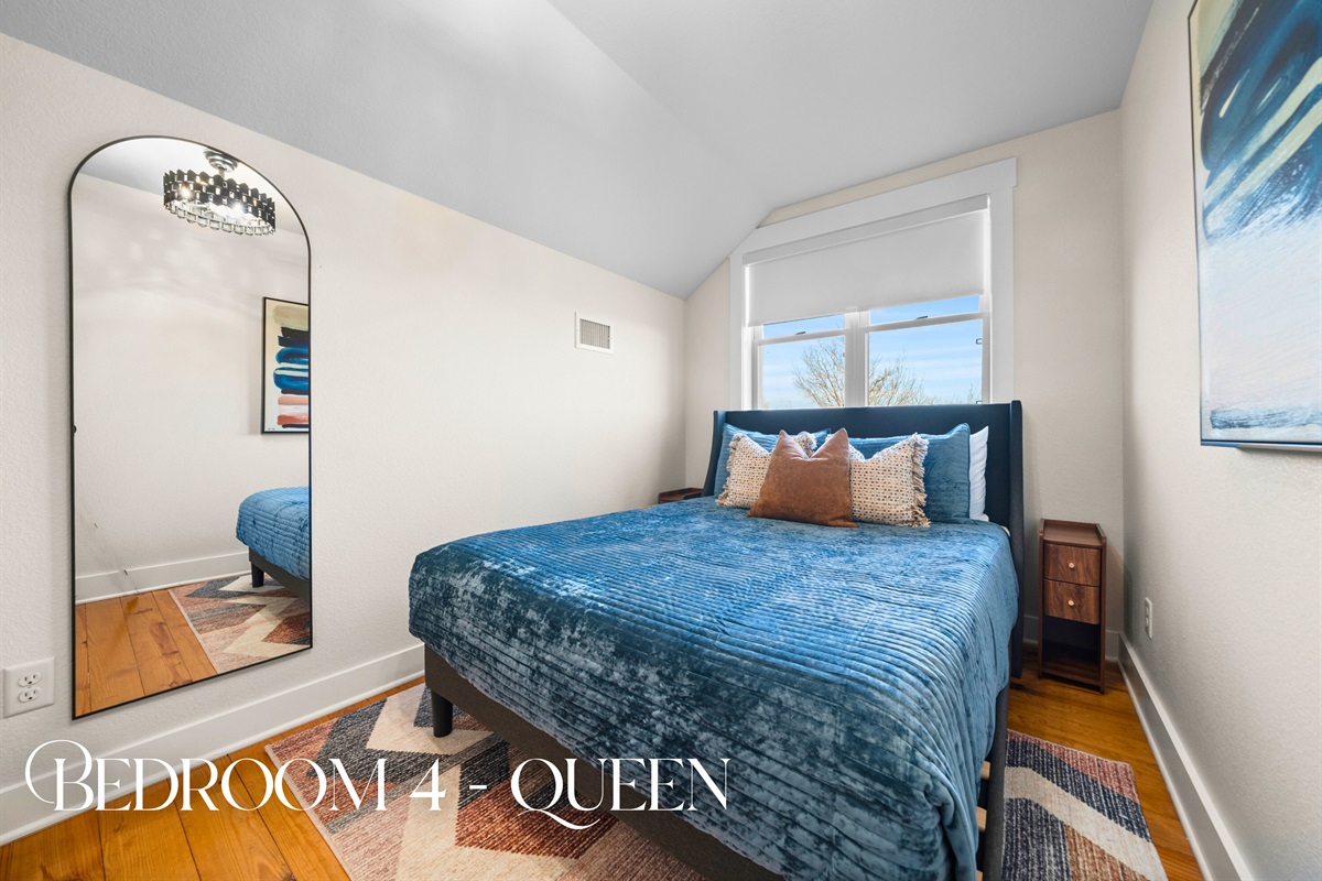 Bedroom four offers a comfortable queen bed tucked beneath charming ceilings, making it a quiet and restful hideaway.
