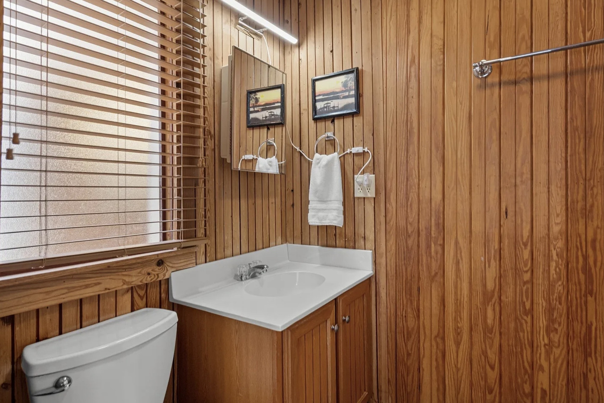 Warm wood details give the upstairs bath a cozy, classic beach house feel. ⭐