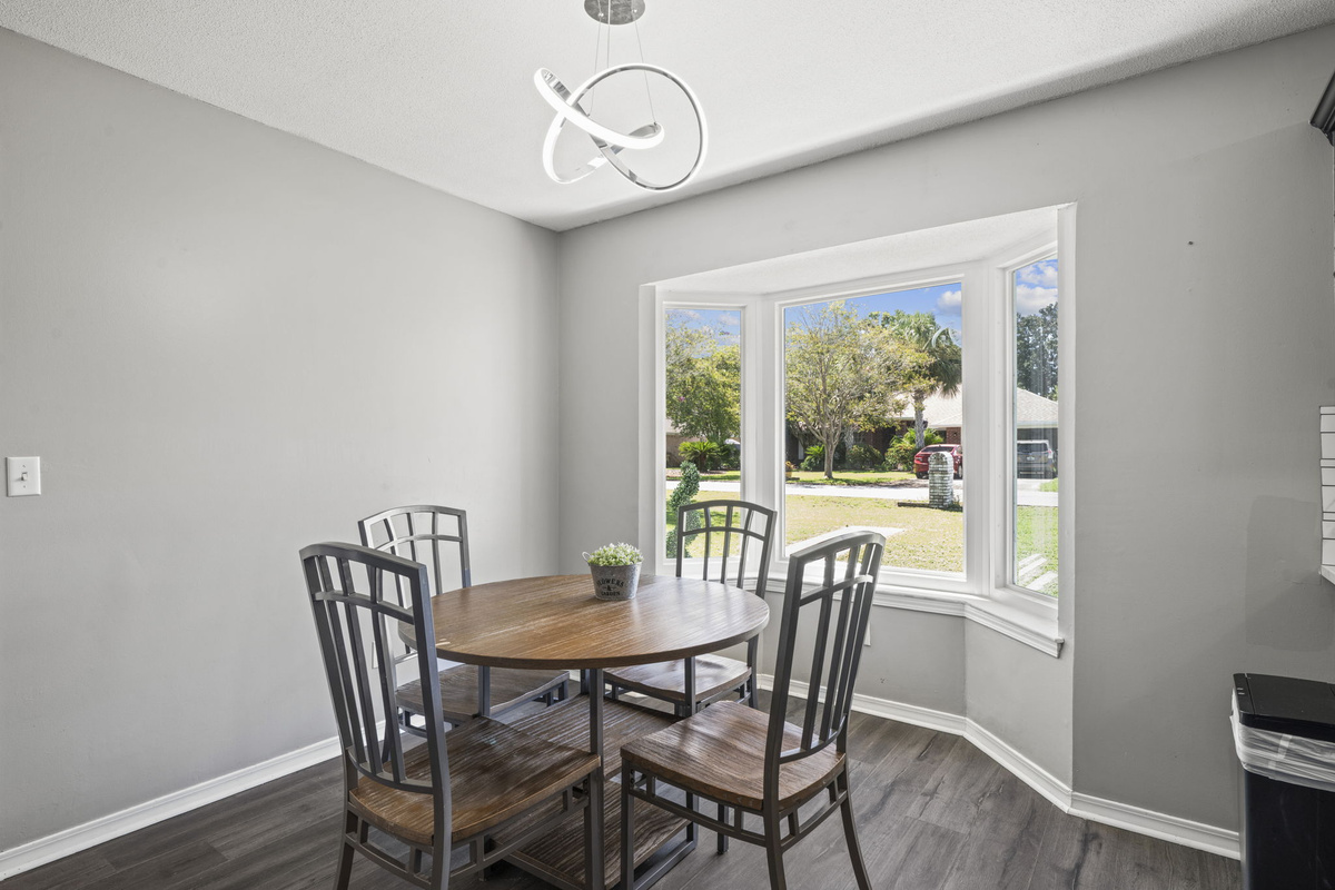 Round table seating for four (or six!) beneath a modern light fixture, framed by natural light streaming in