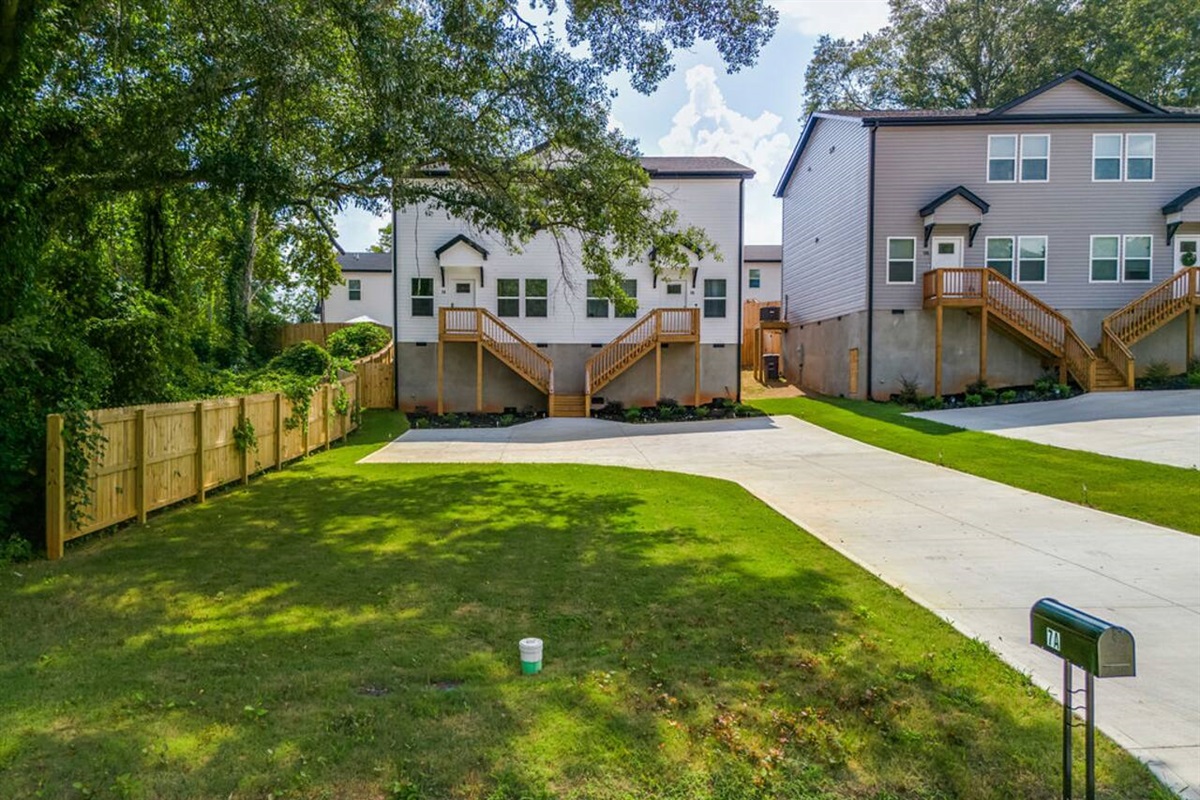 Enjoy the front yard with vibrant green grass, a driveway, and a cement parking pad for easy and convenient parking."