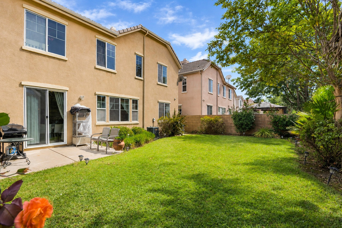Backyard with a grassy lawn, patio seating, and plenty of space to enjoy the fresh air.