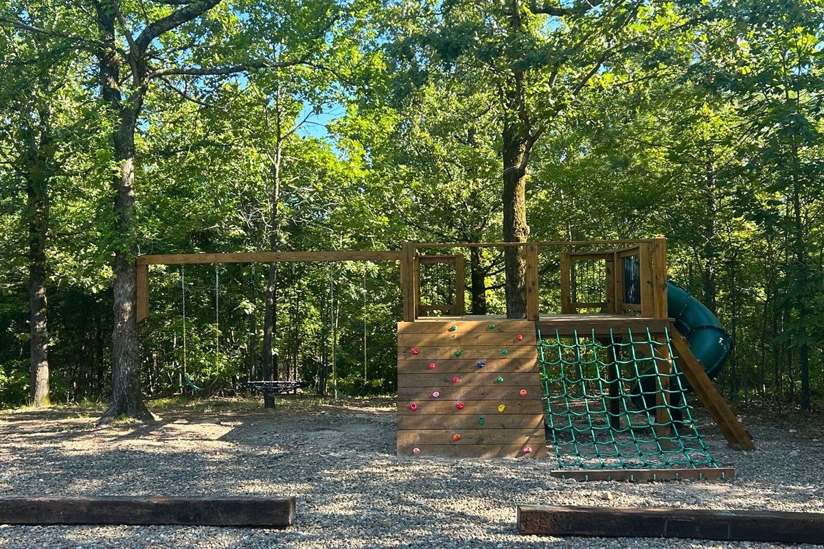 Large playset with climbing walls, rope net, slide, and clubhouse.