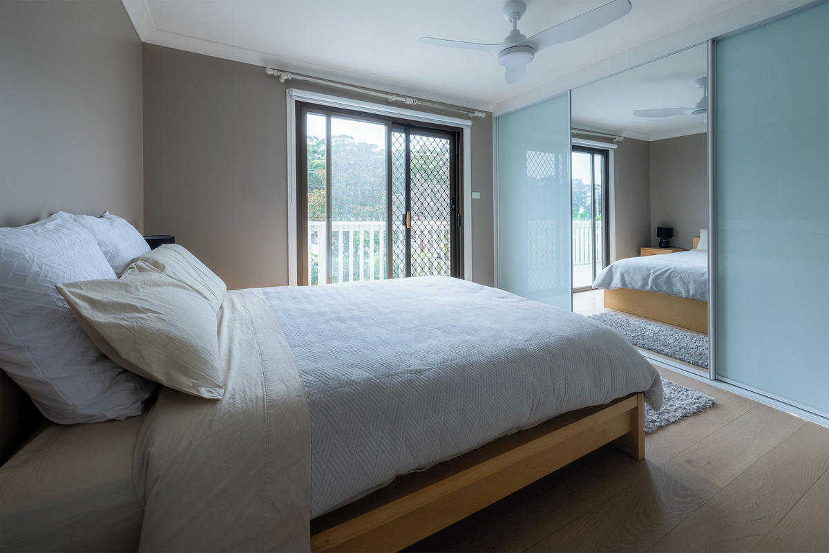 Balcony access, timber floors and mirrored storage give this Luna’s Sanctuary bedroom a bright, open feel for slower coastal mornings.
