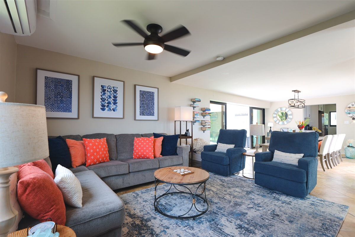 Bright and open living area with a ceiling fan and AC unit to keep it cool when you need but also flows effortlessly into the outdoors.