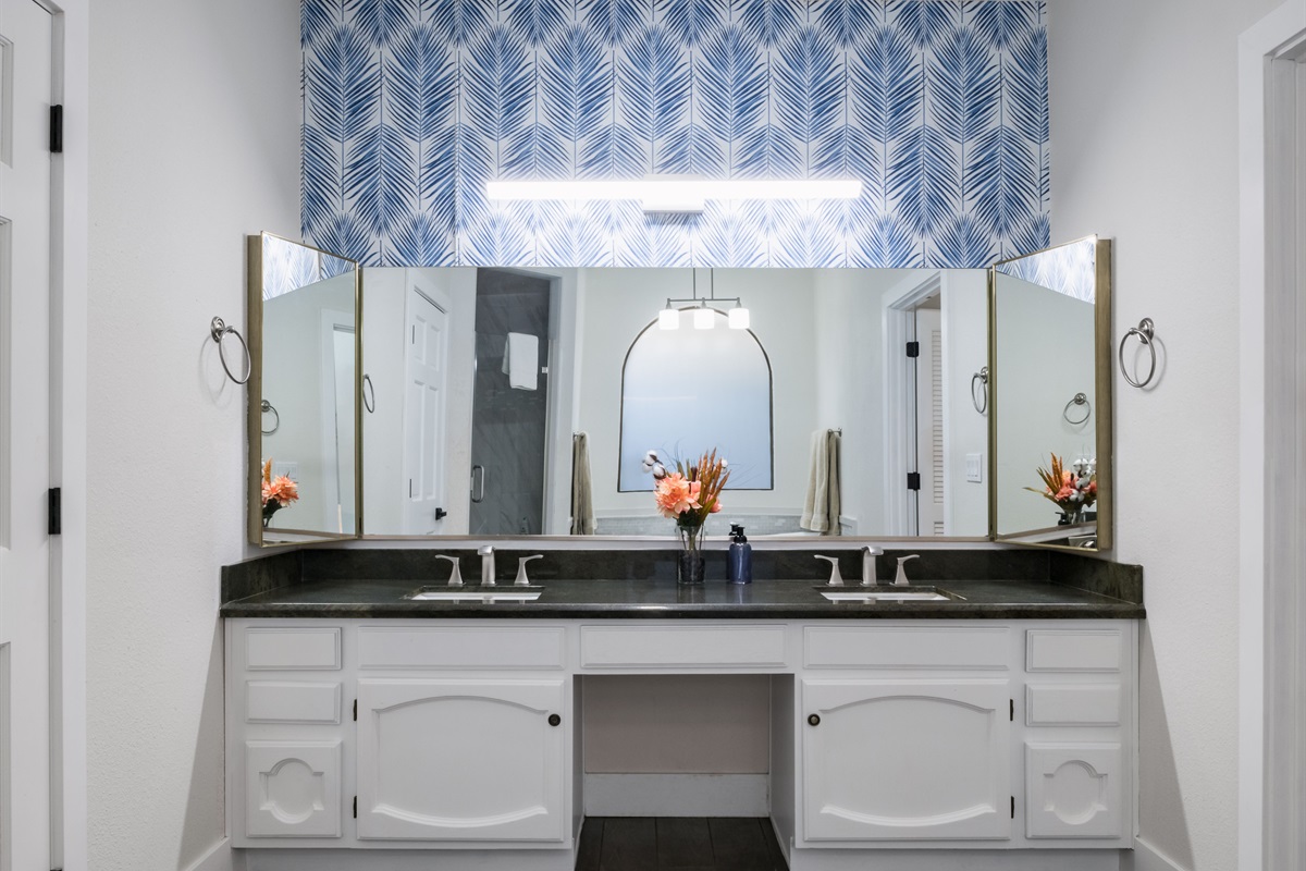 Treat yourself to a stylish bathroom sanctuary with bold wallpaper, dual sinks, and a deep soaking tub perfect for winding down.