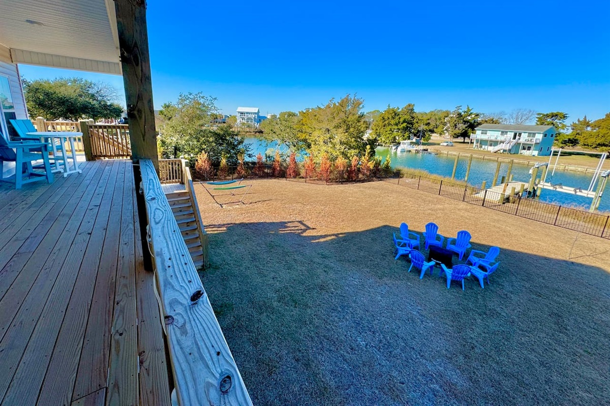 Private backyard dock with boat lift and fillet table, fenced-in backyard, fire pit with Adirondack chairs, hammocks, propane grill, picnic table, outdoor shower, expansive waterfront back deck, neighborhood boat ramp and dock