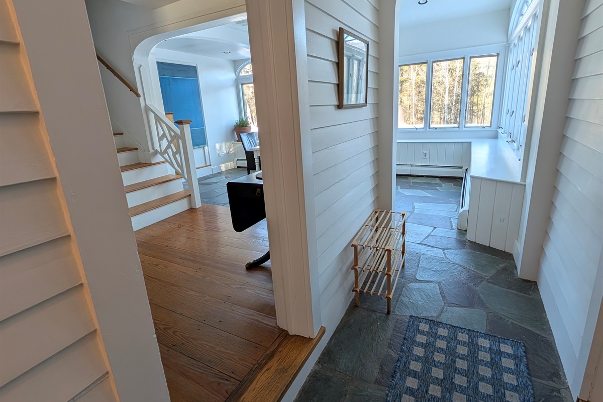 An airy passageway connects cozy living spaces to a light-filled sunroom, perfect for morning coffee or quiet reading.