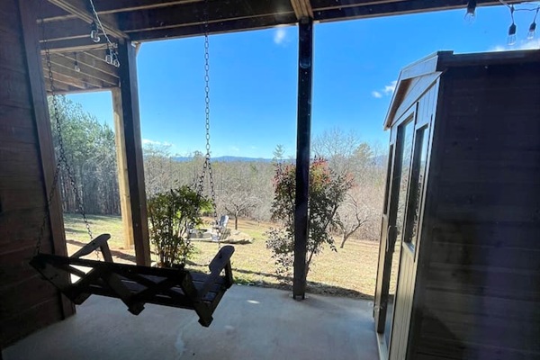 Patio off of the basement bedroom with a bench swing and infrared sauna, and views of the backyard with firepit and orchard trees!