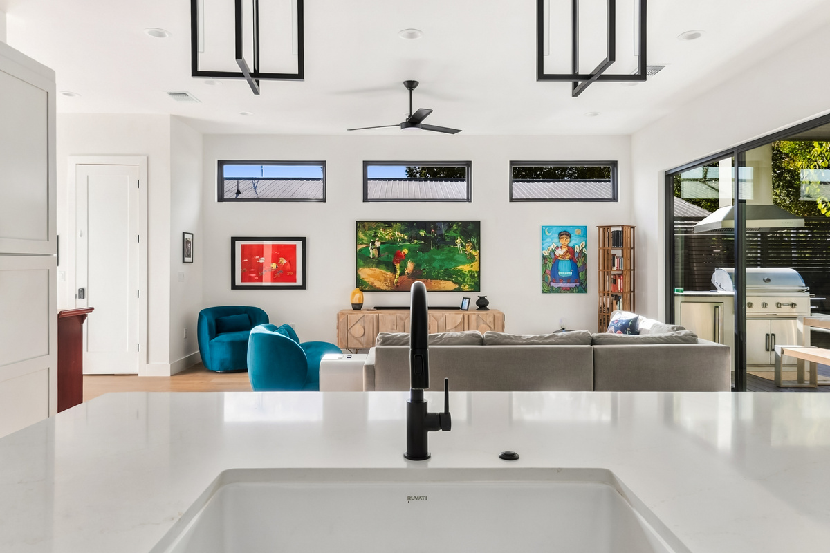 Kitchen flows seamlessly into the living room, framed by colorful artwork.