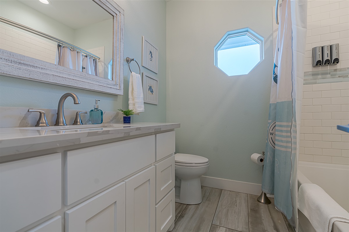 Full bathroom off the kitchen hallway. Each shower is equipped with shampoo, conditioner, and body wash.