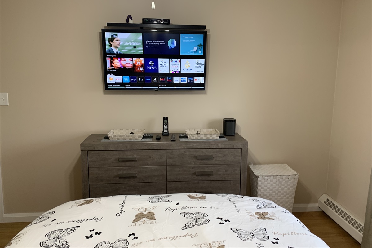 Second bedroom has large mirrored closet, queen bed set, dresser, end table and smart TV and Sonos speaker.