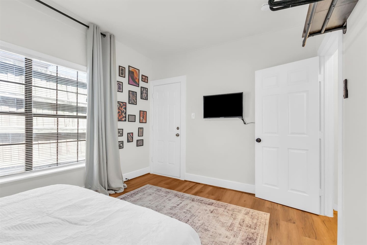 Bedroom with full bed, TV, and large window with room darkening shades.