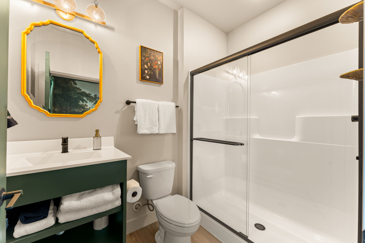 Full Bathroom with Walk-In Shower
    A clean and modern full bathroom featuring a spacious glass-enclosed shower, generous vanity space, fresh linens, and warm decorative touches.