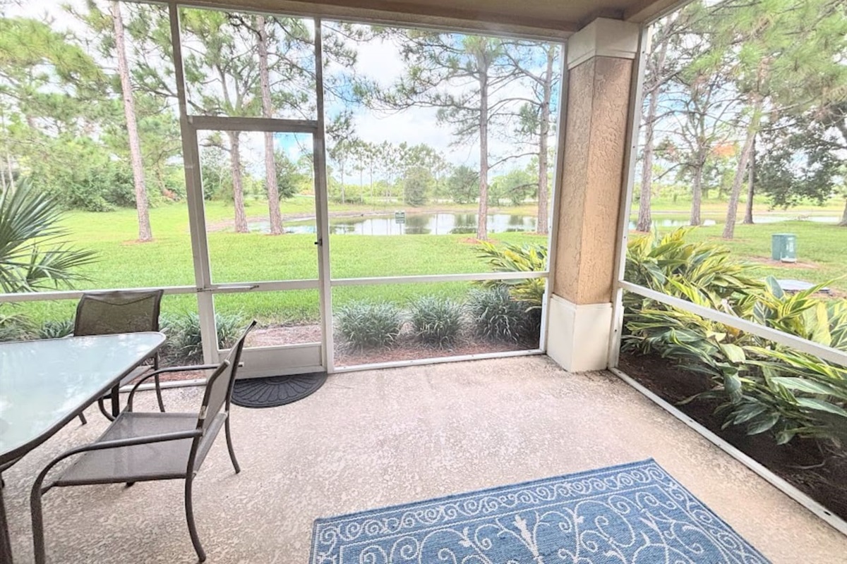 Private screened patio with outdoor seating and peaceful views of the surrounding green space.