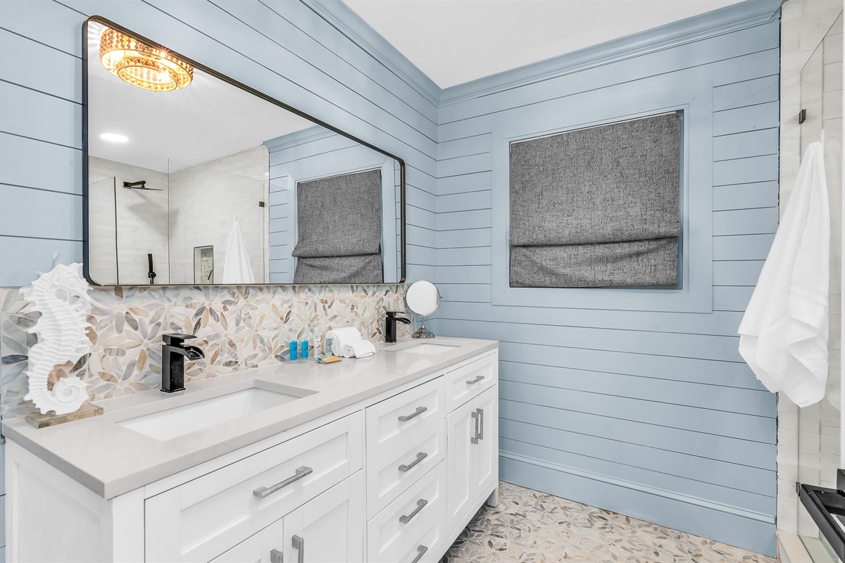 Primary Bathroom: This spa-inspired bathroom features sleek coastal design with a walk-in glass shower, modern fixtures and soft natural light- creatig a serene retreat for relaxation and rejuvenation