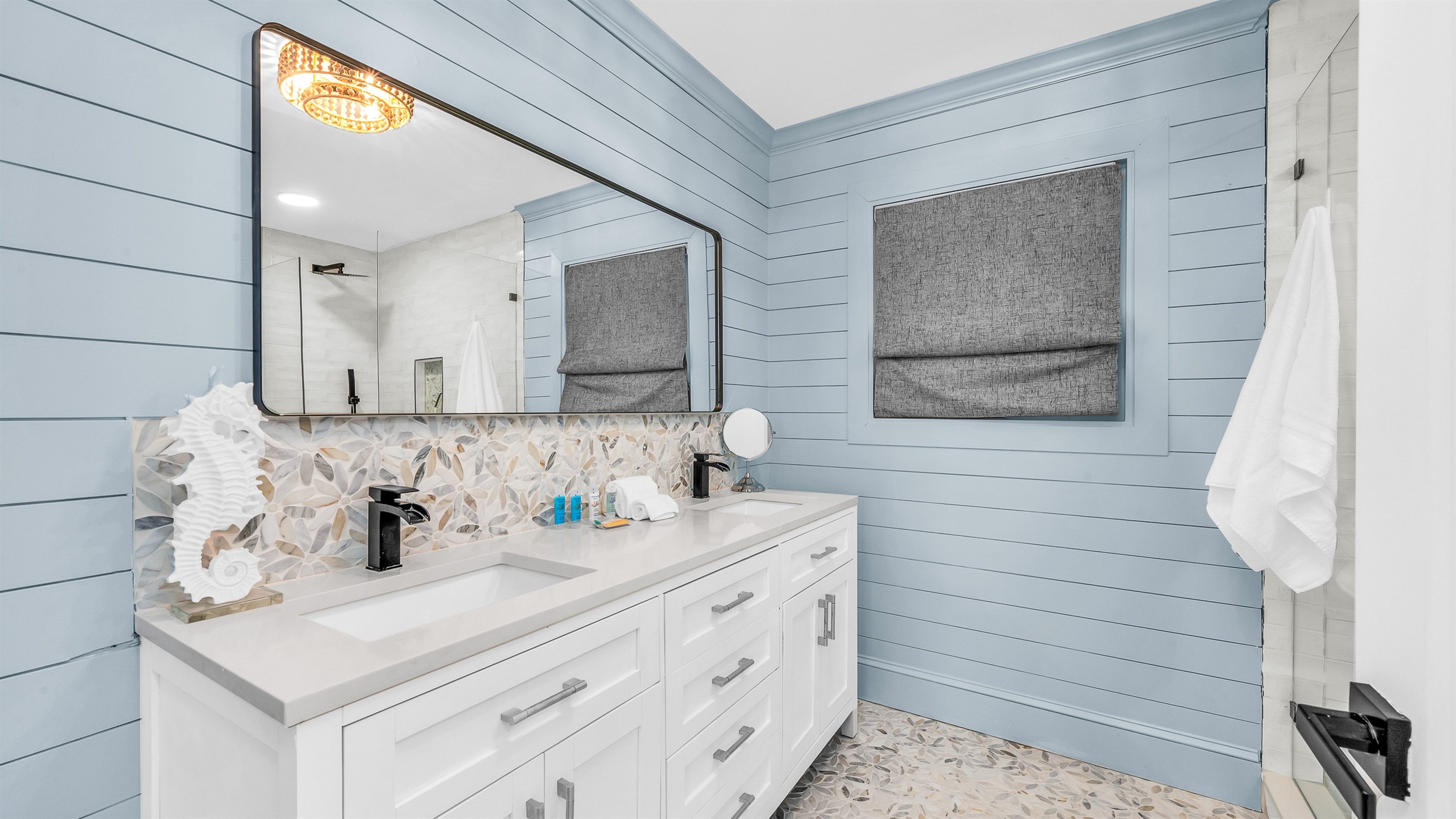 Primary Bathroom: This spa-inspired bathroom features sleek coastal design with a walk-in glass shower, modern fixtures and soft natural light- creatig a serene retreat for relaxation and rejuvenation