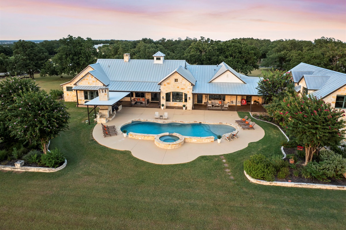 Bird's-eye perspective of a beautiful home and its expansive grounds, featuring a sparkling swimming pool and hot tub.