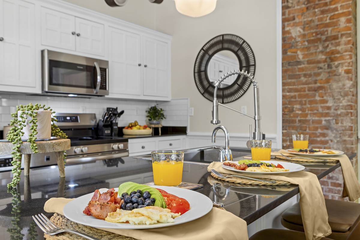 Dark stone countertops, a stainless steel sink, and island seating provide everything you need to prepare and enjoy a big group breakfast.