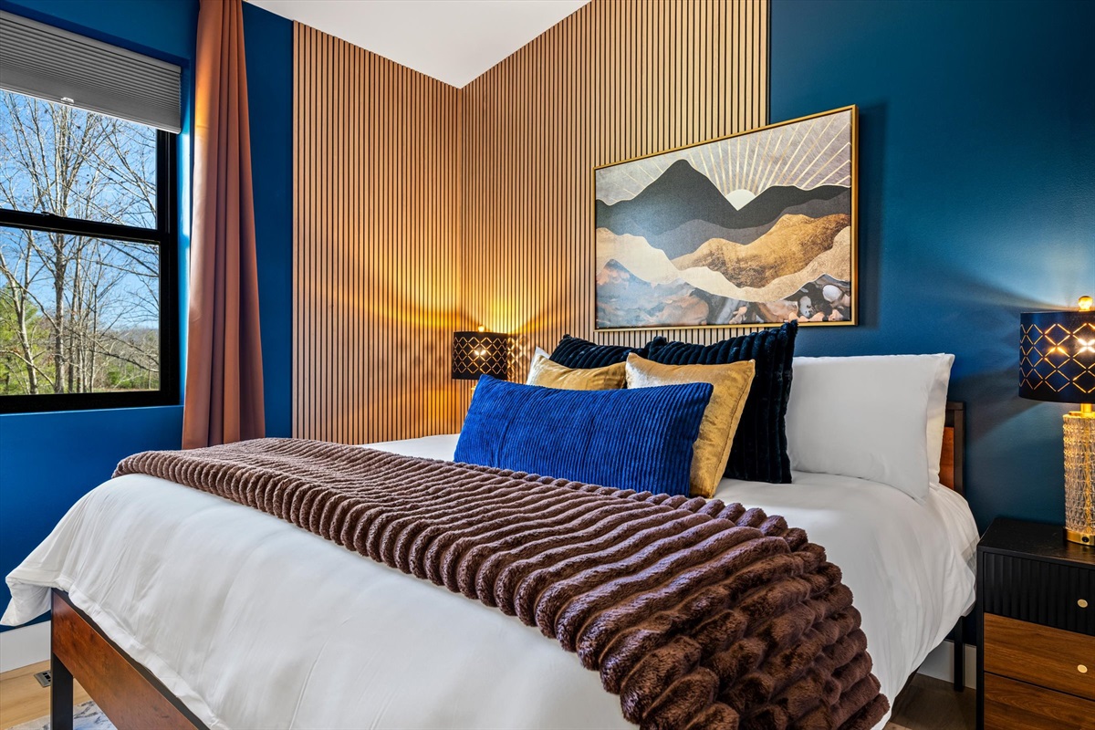 {King Bedroom} A calm, private retreat — king bed, ensuite bath, and plush robes for a spa-like unwind, framed by Blue Ridge artwork and warm wood slat detailing.
