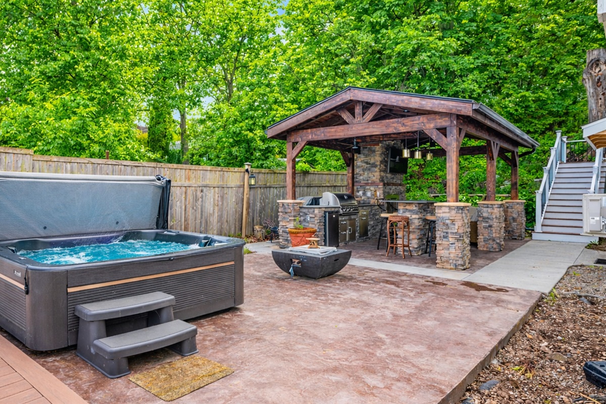 Entertain in style with a covered stone kitchen, grill, hot tub, and fire feature—your backyard retreat 🍔🔥🍷