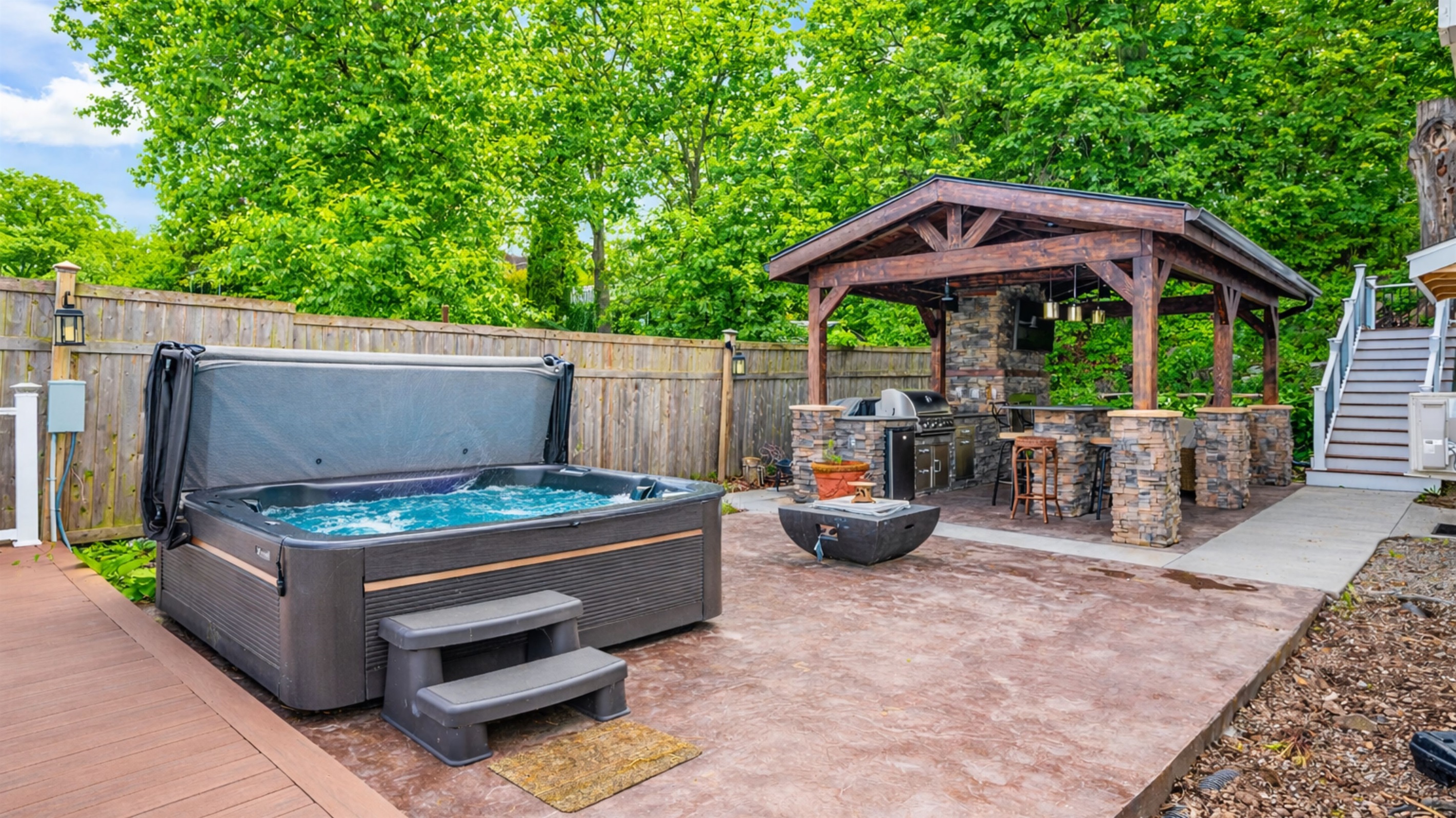 Entertain in style with a covered stone kitchen, grill, hot tub, and fire feature—your backyard retreat 🍔🔥🍷