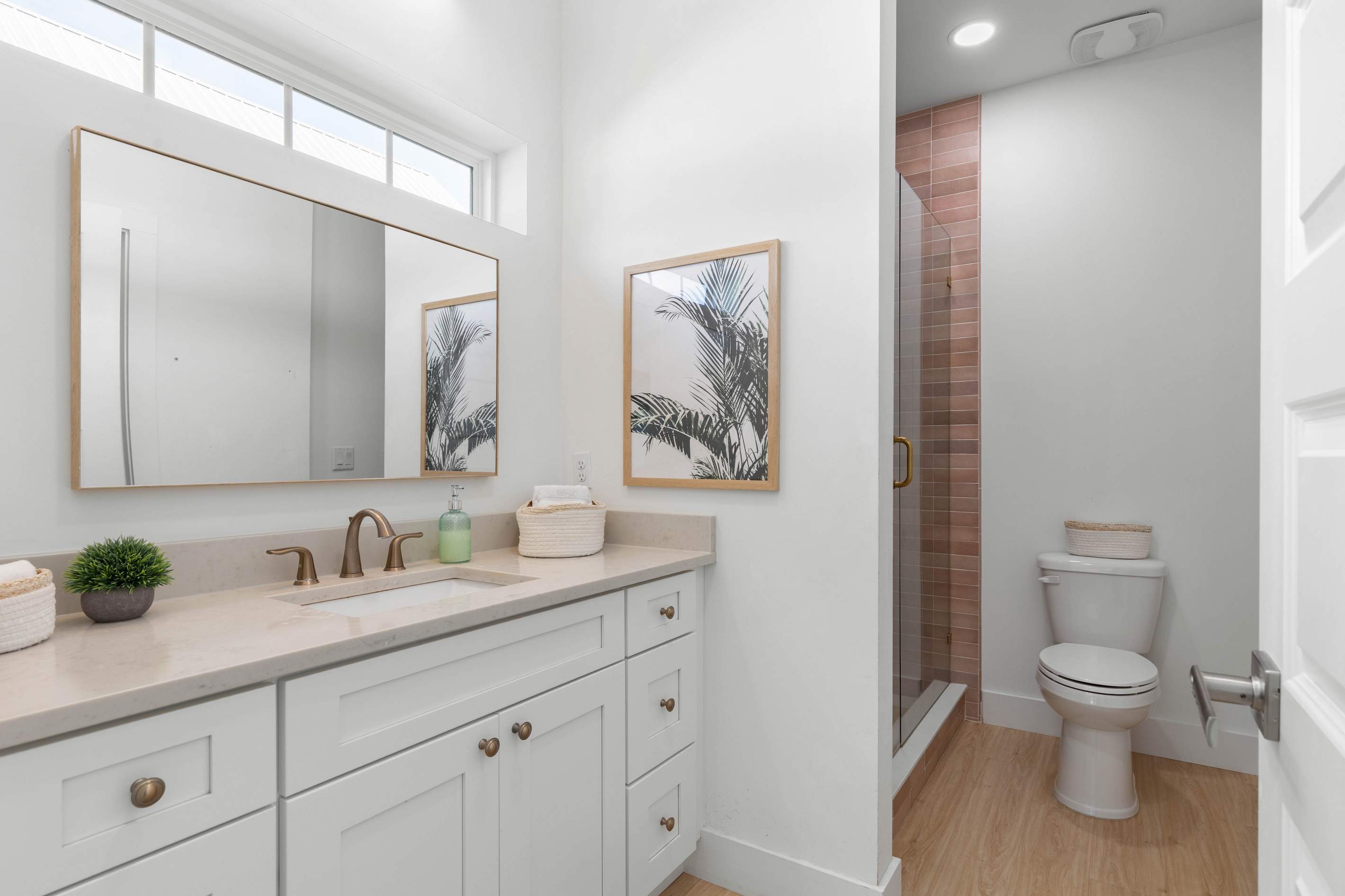 Clay-toned tile warms the whole room, and the transom windows up high bring the light in without giving anything away. Counter space for everybody's things, and a walk-in shower that clears sand quickly.