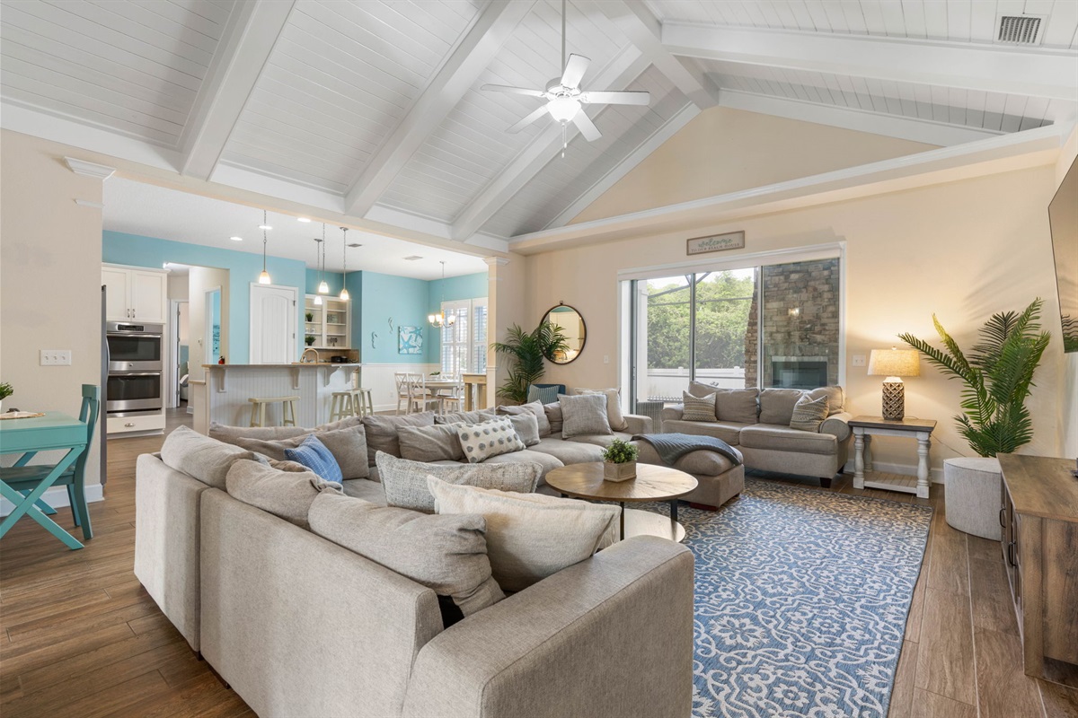 After the beach, toss open the sliders, settle into the oversized sectional, and let the whole house come together—snacks at the island, a movie in the living room, and the glow of the outdoor fireplace just beyond the glass.