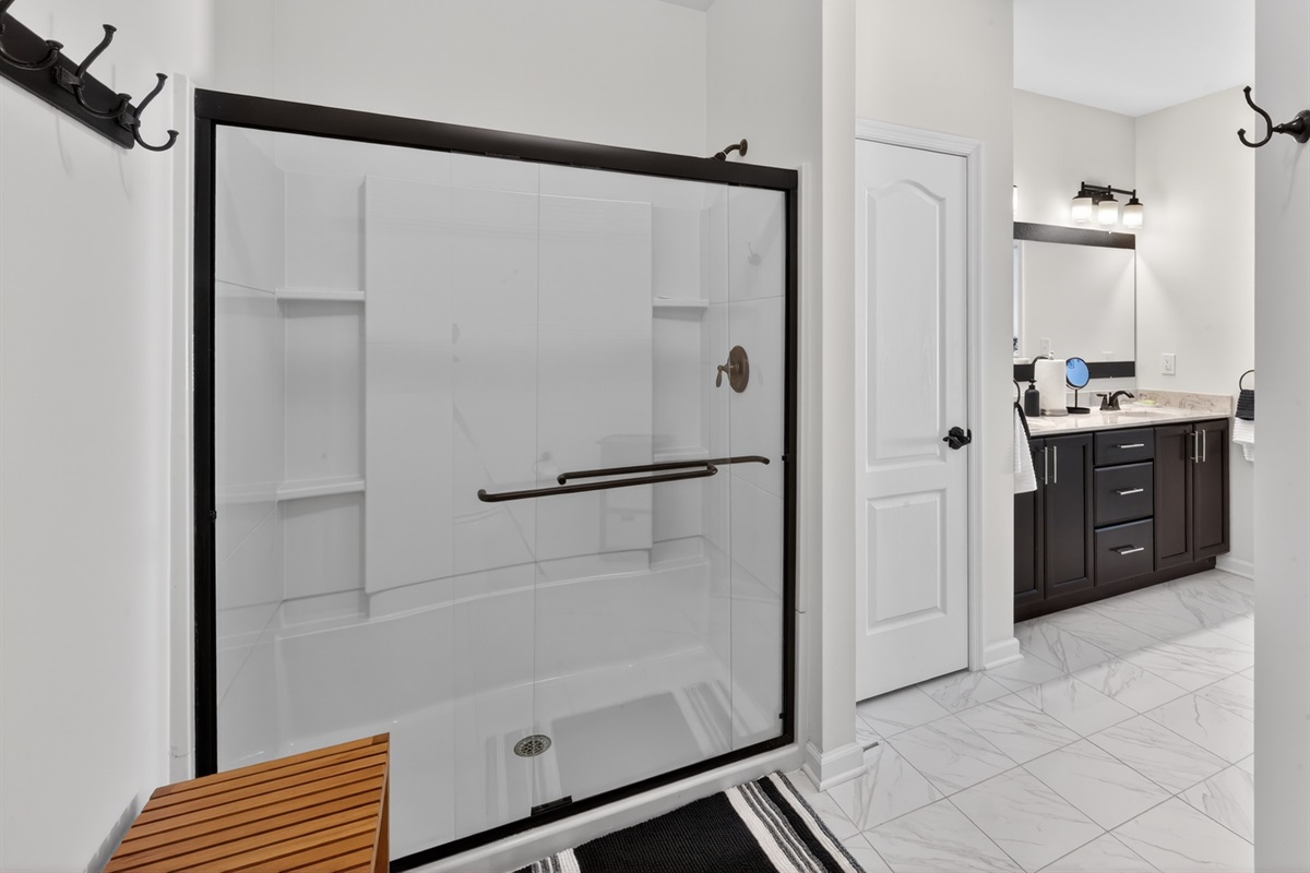 Large shower with bench and shower hooks, toilet tucked around the corner for even more privacy