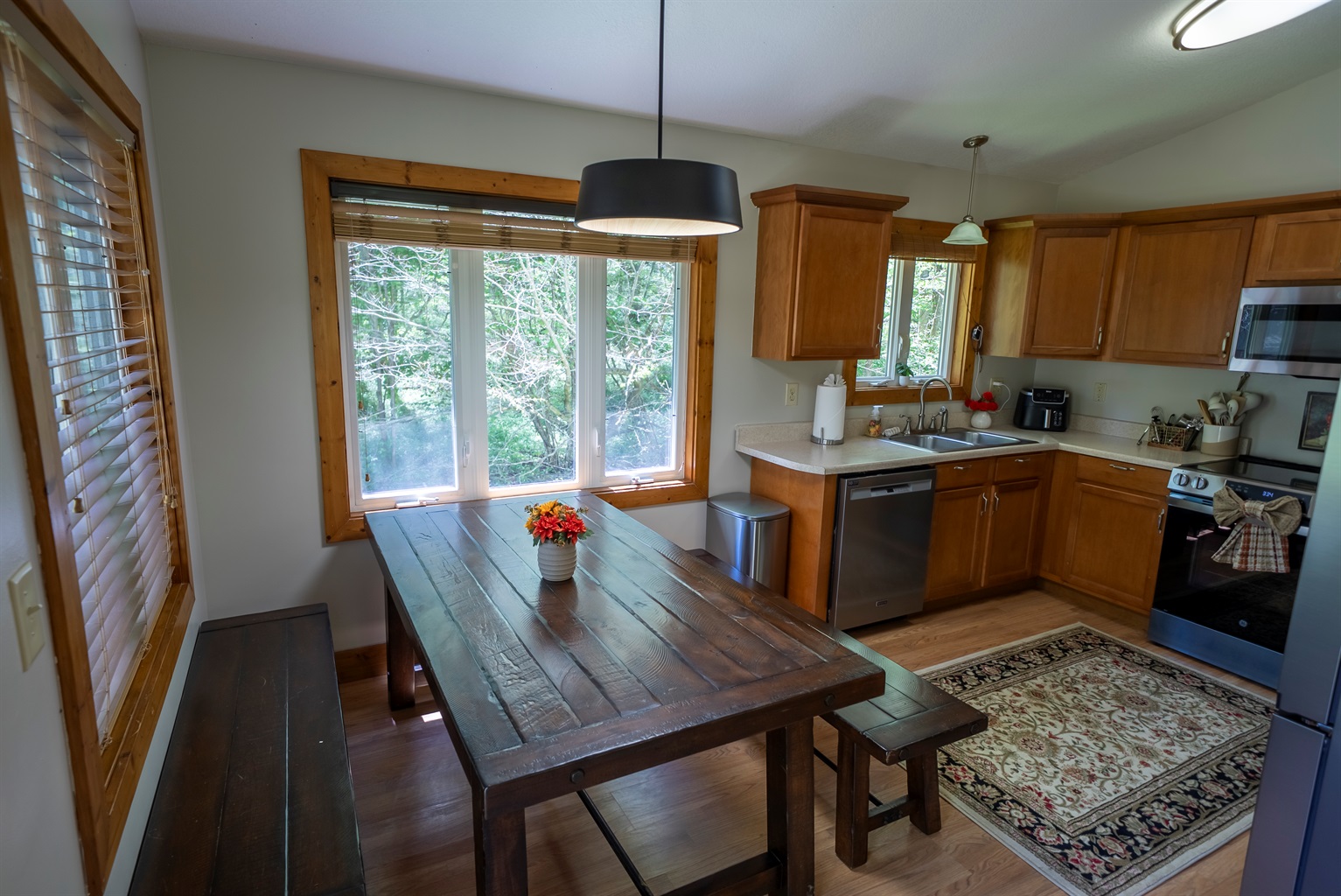 A cozy dining nook with bench seating and corner windows that bring the outdoors in, including peaceful creek views.