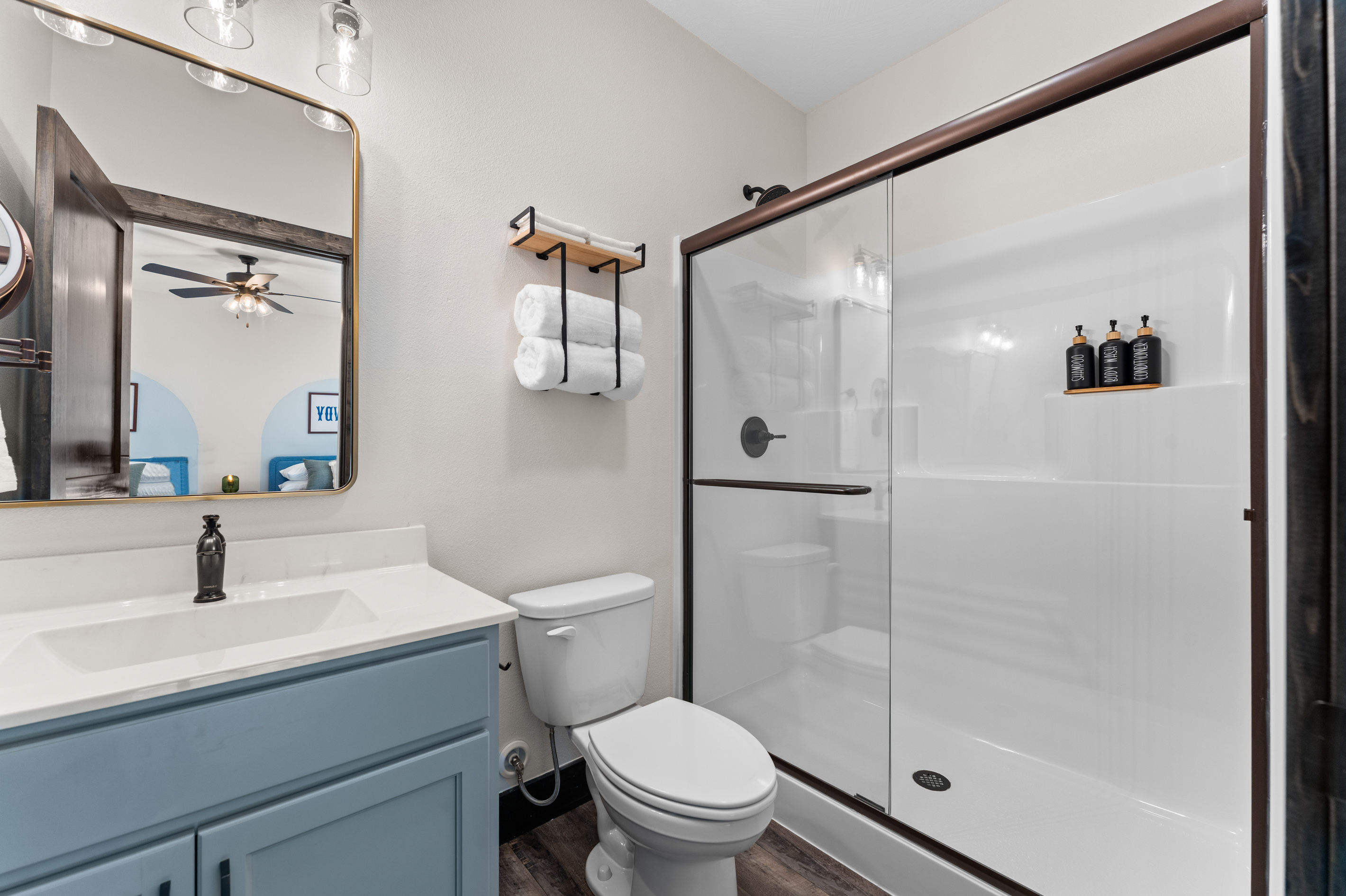 A Austin room ensuite bathroom with a walk-in glass shower and fresh towels sits beside the twin room.